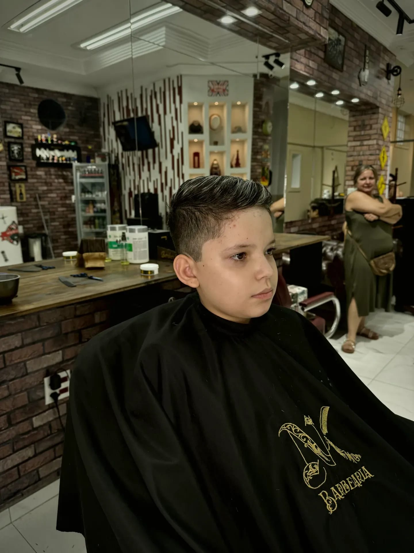 Bancada de madeira e parede de tijolos no interior da NK Barbearia